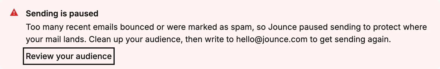 The red banner at the top of the Emails page, reading Sending is paused, with its Review your audience link ringed.